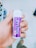 A hand holds a small cylindrical container with a purple label that reads 'Xylitol' and 'Rasa Bubblemint'. The background shows rows of shelves, indicating a store setting.