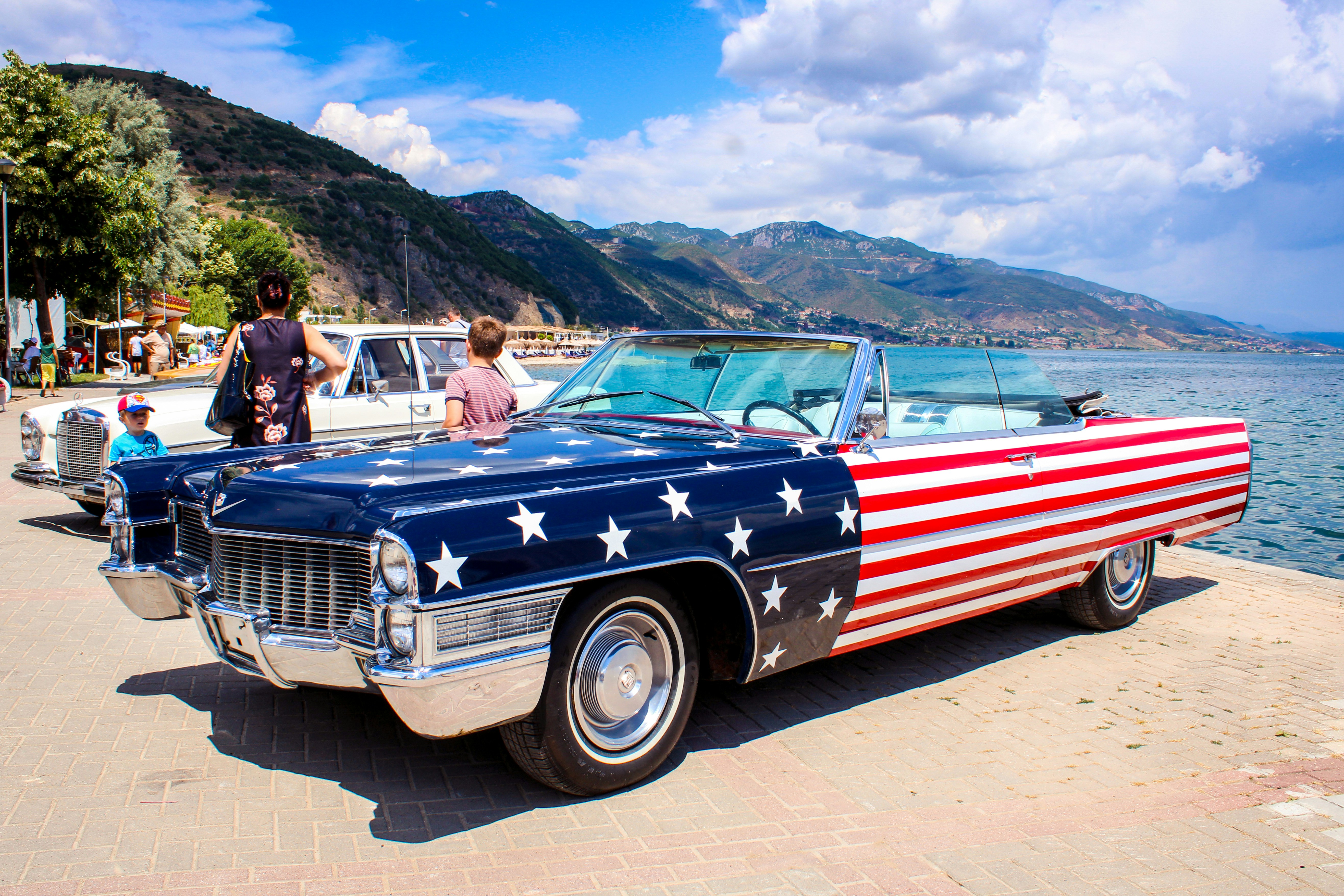 people riding red and white vintage car during daytime