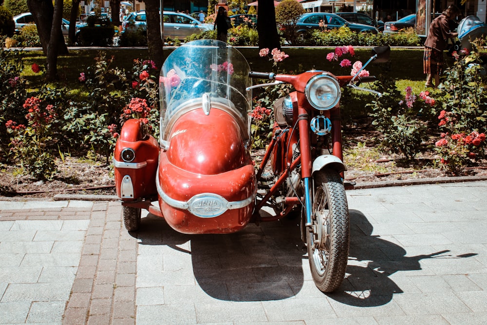 Motocicletta rossa e nera parcheggiata sul marciapiede durante il giorno