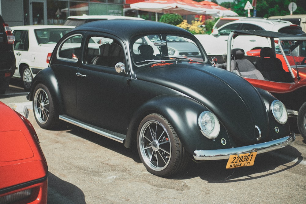 black volkswagen beetle parked on gray concrete floor during daytime