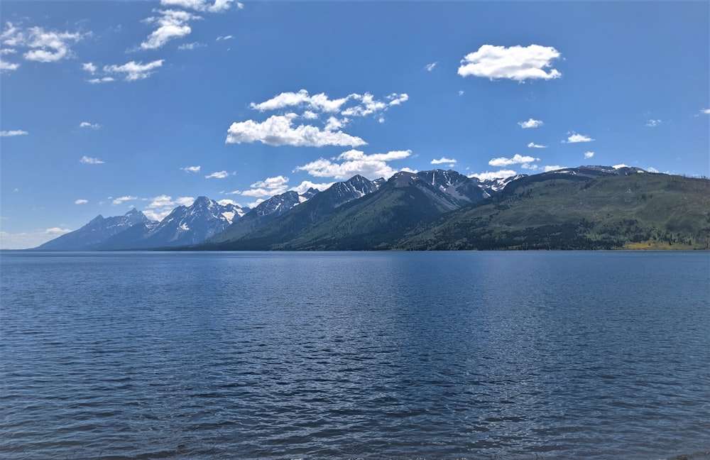 body of water near mountain under blue sky during daytime