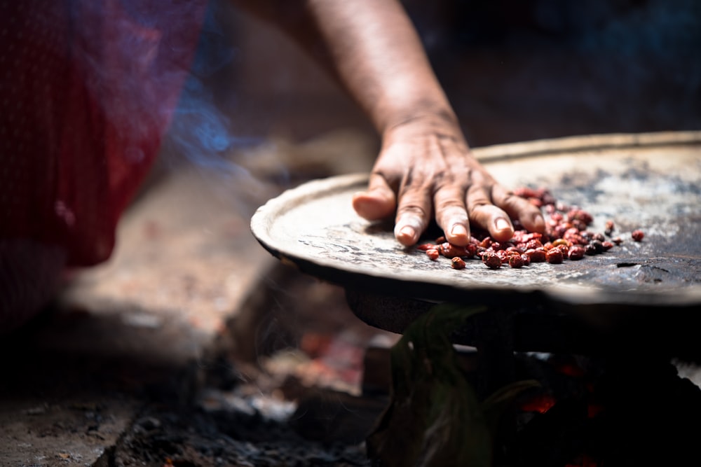 person holding white ceramic plate with brown food