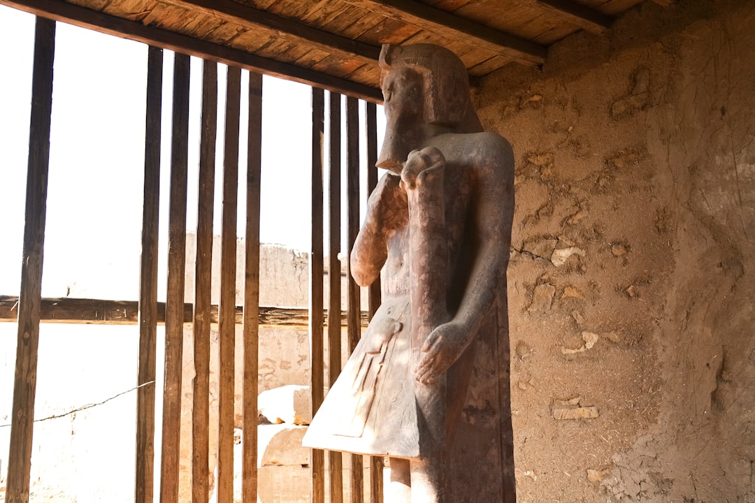 brown concrete statue near brown wooden fence during daytime