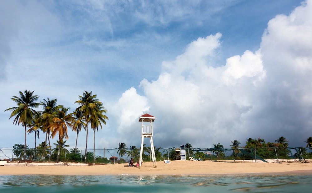 Weißer und orangefarbener Rettungsschwimmerturm am Strand tagsüber