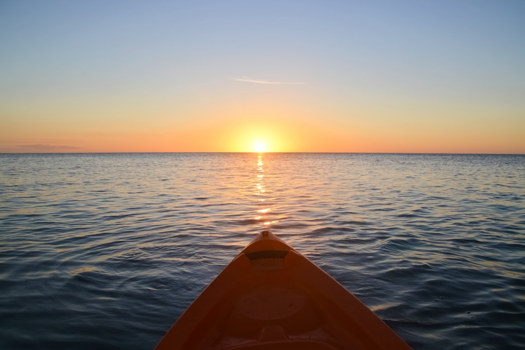 orange kayak on sea during sunset