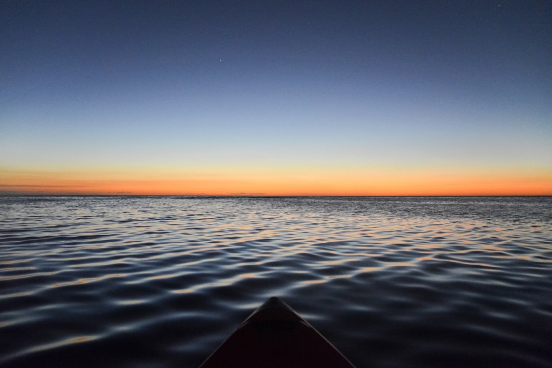 black boat on sea during sunset