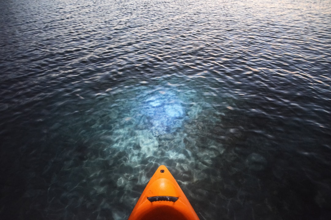 orange kayak on body of water
