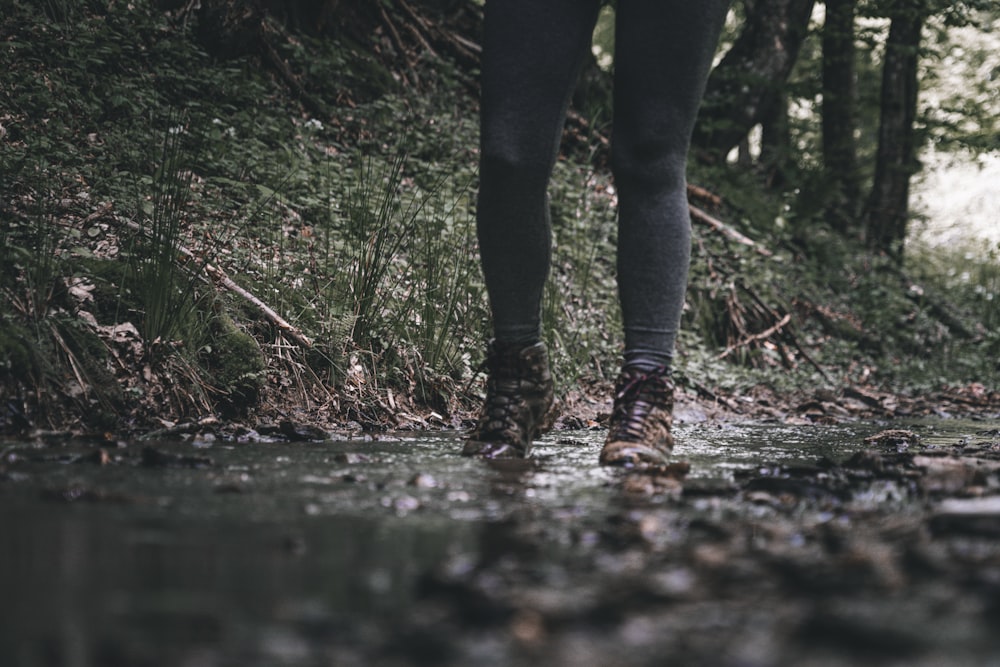 person in black pants and brown boots standing on water