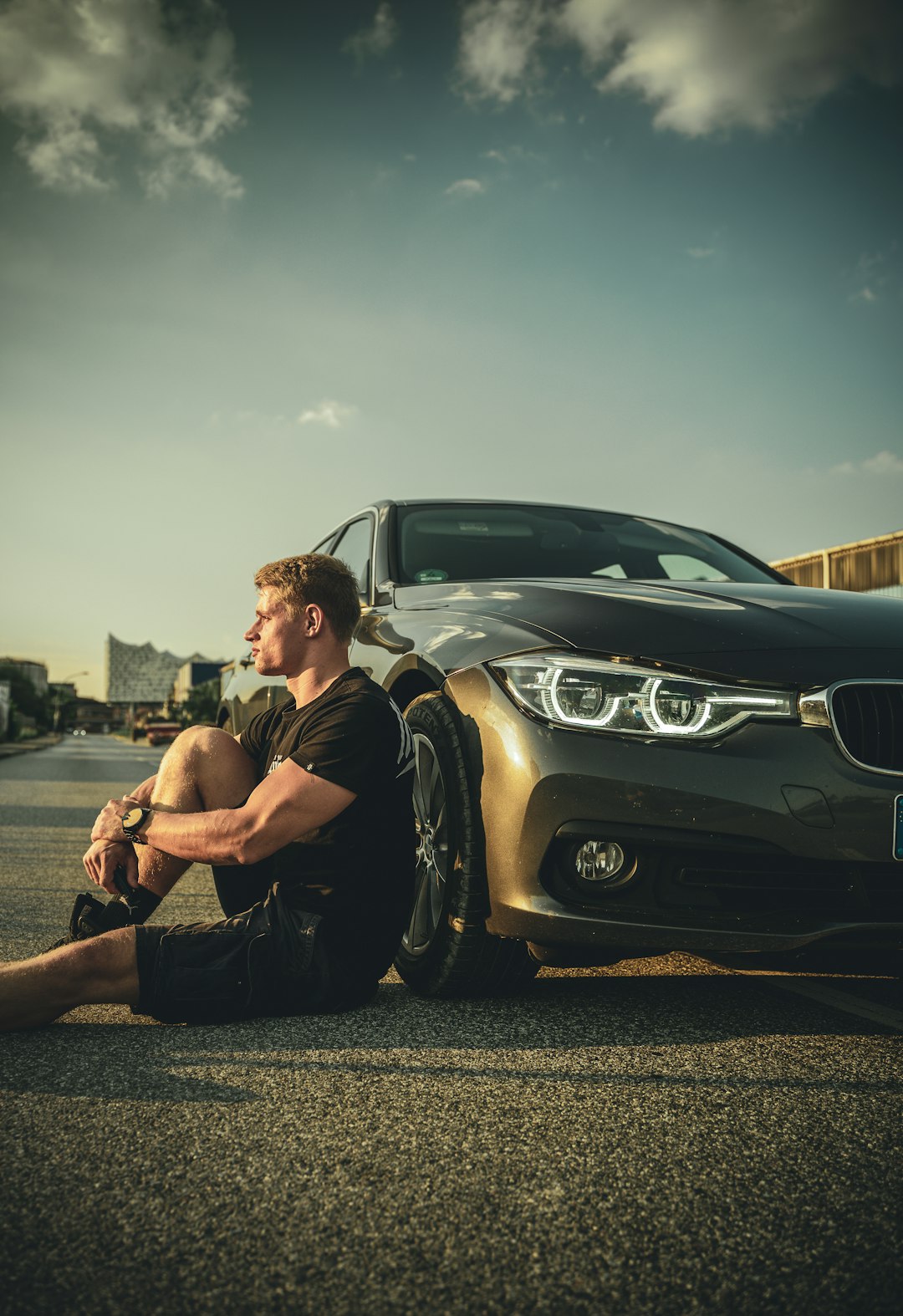 man in black t-shirt sitting on black mercedes benz car