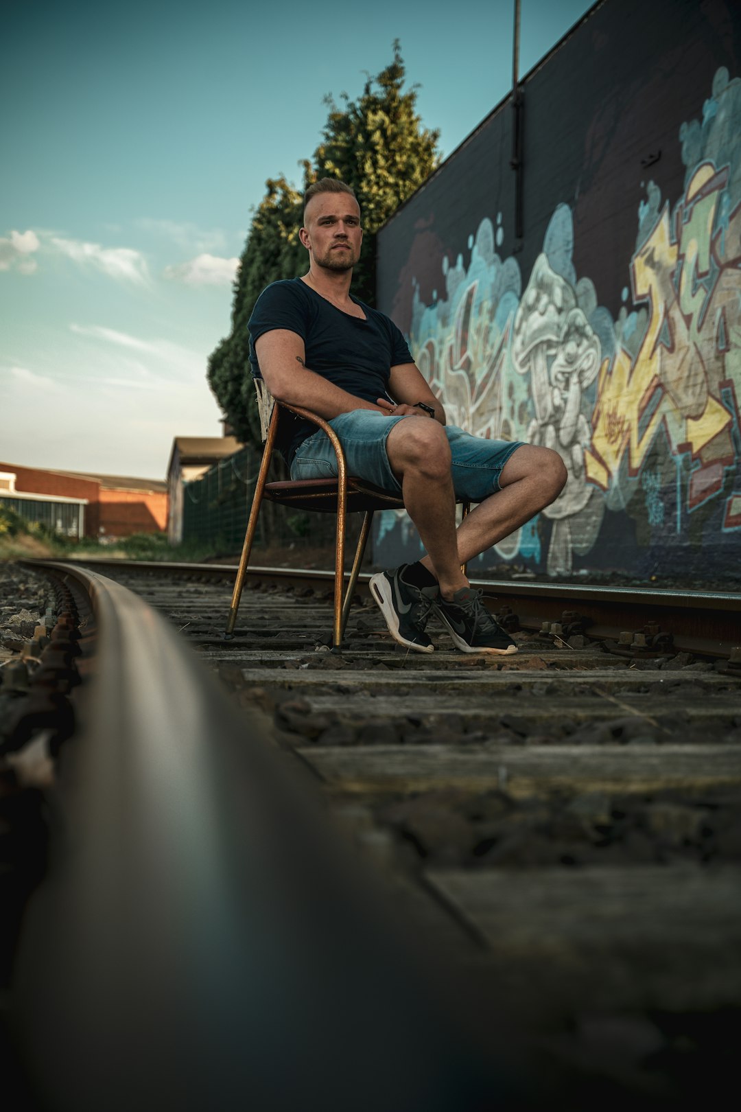 man in black jacket and blue denim jeans sitting on brown wooden chair