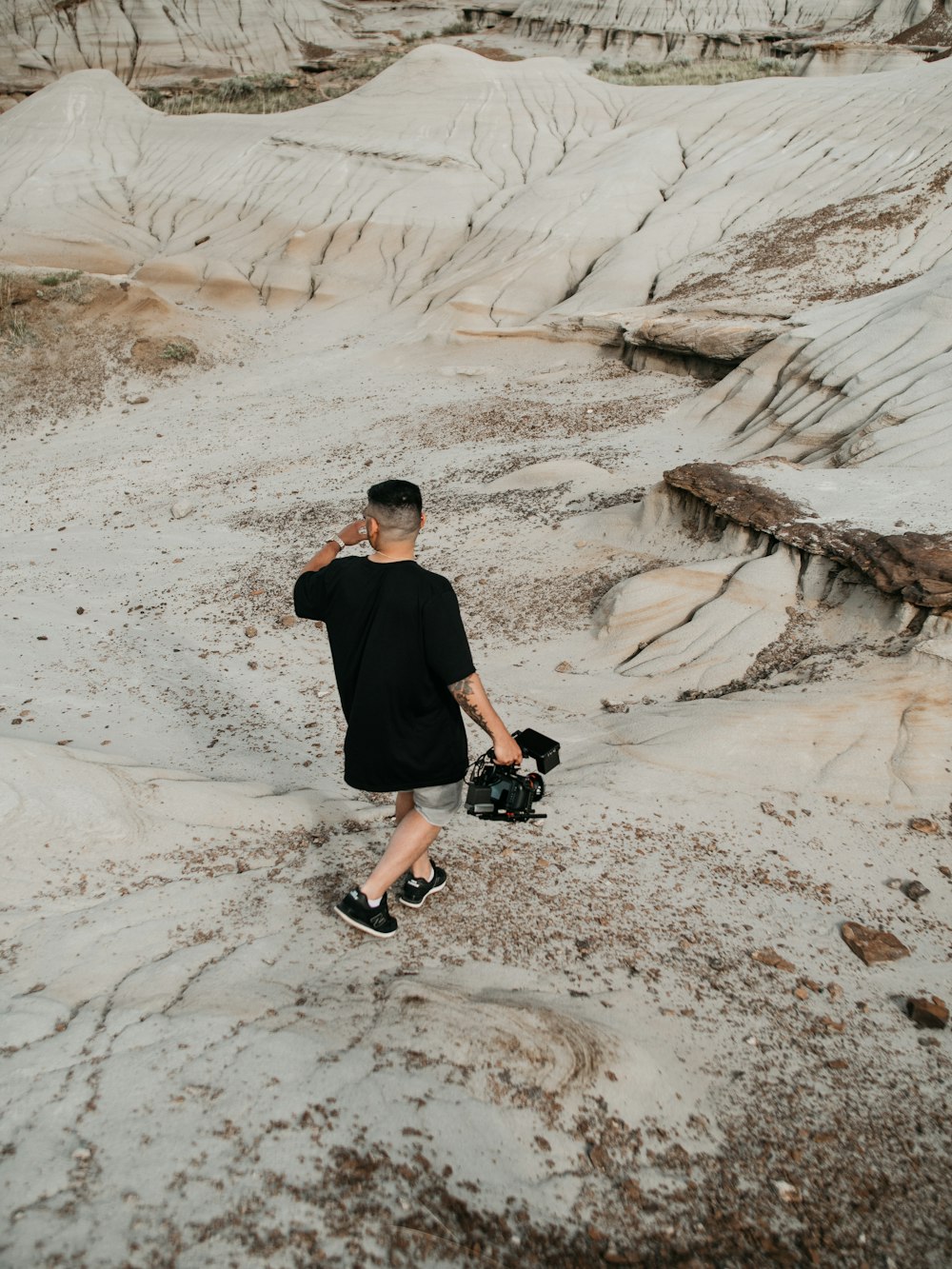 man in black t-shirt and black pants sitting on brown rock formation during daytime
