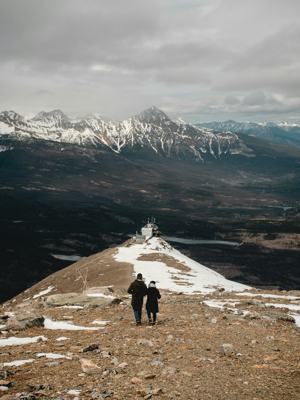 2 people standing on gray rock mountain during daytime