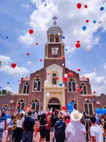 people in front of brown and white cathedral under cloudy sky during daytime