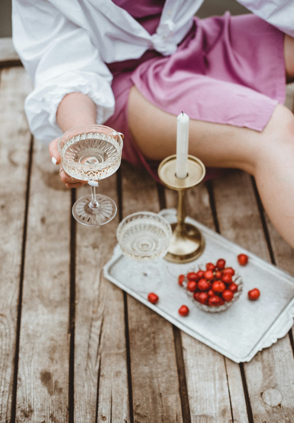 person holding white ceramic bowl with strawberries and grapes