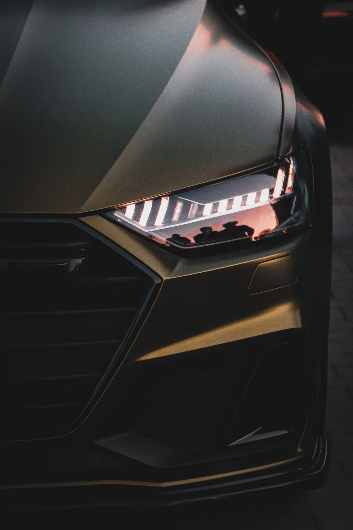 Front grille and headlight of a dark green Audi RS 6 in a showroom
