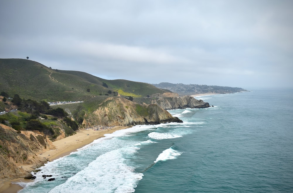 green and brown mountain beside sea during daytime