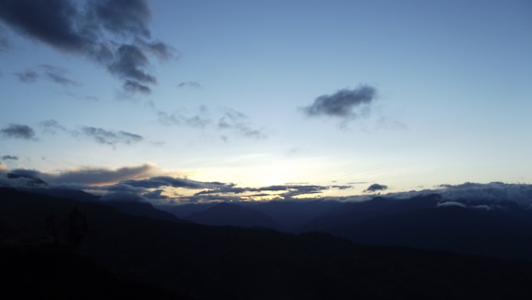 A serene landscape silhouette fading into a black horizon under soft light.