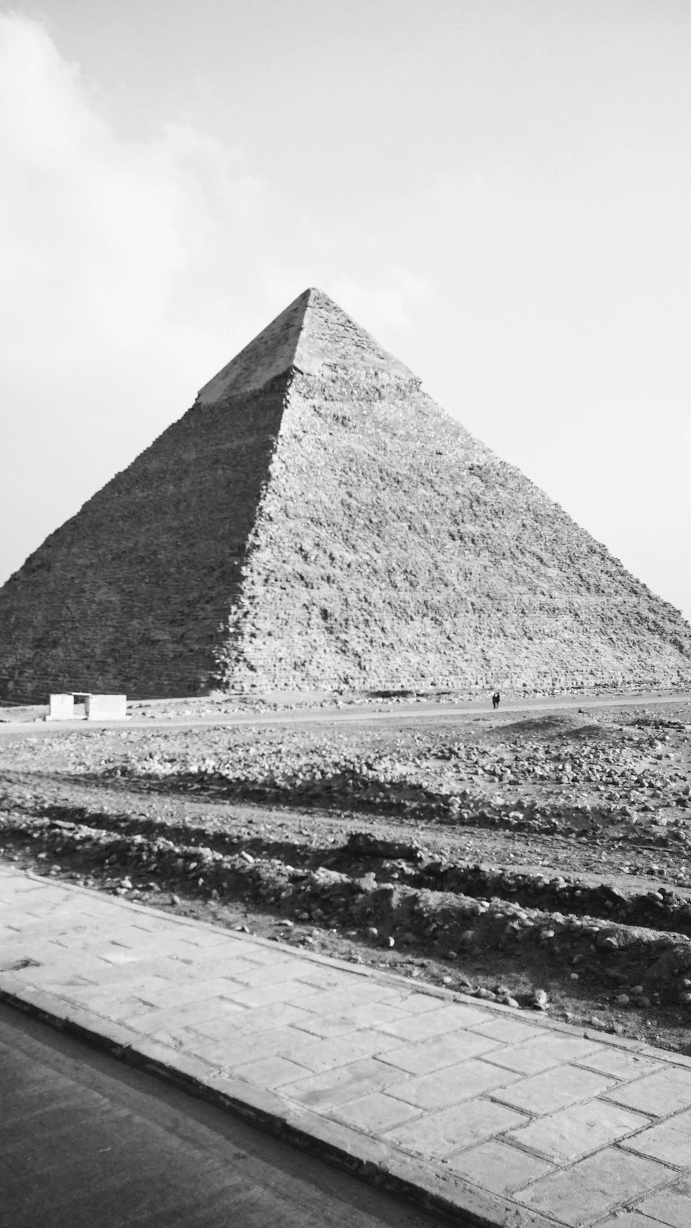 grayscale photo of pyramid under cloudy sky