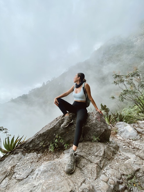 woman in black tank top and black leggings sitting on rock