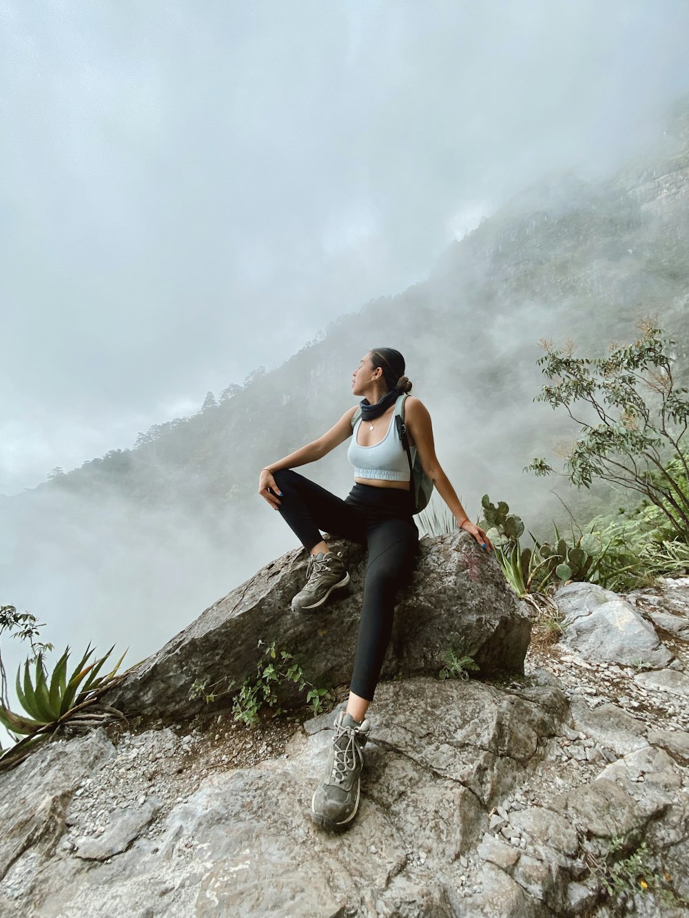 woman in black tank top and black leggings sitting on rock