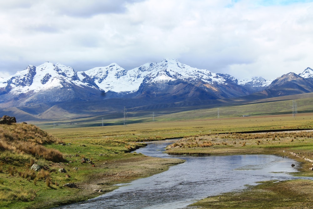 green grass field near lake and snow covered mountain during daytime