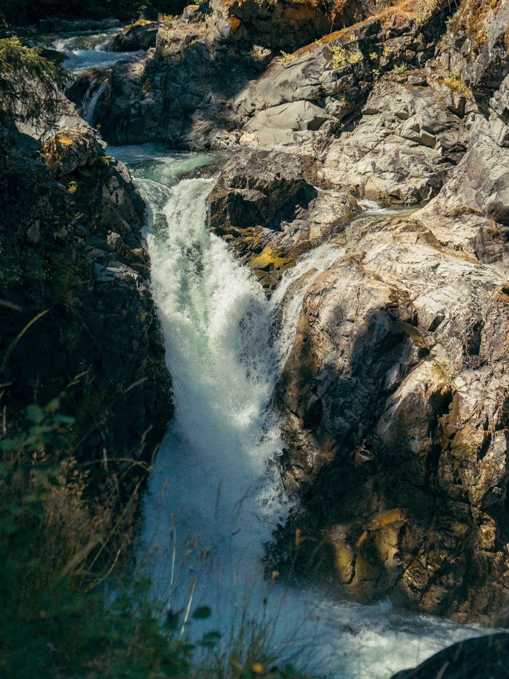 water falls between rocky mountain during daytime