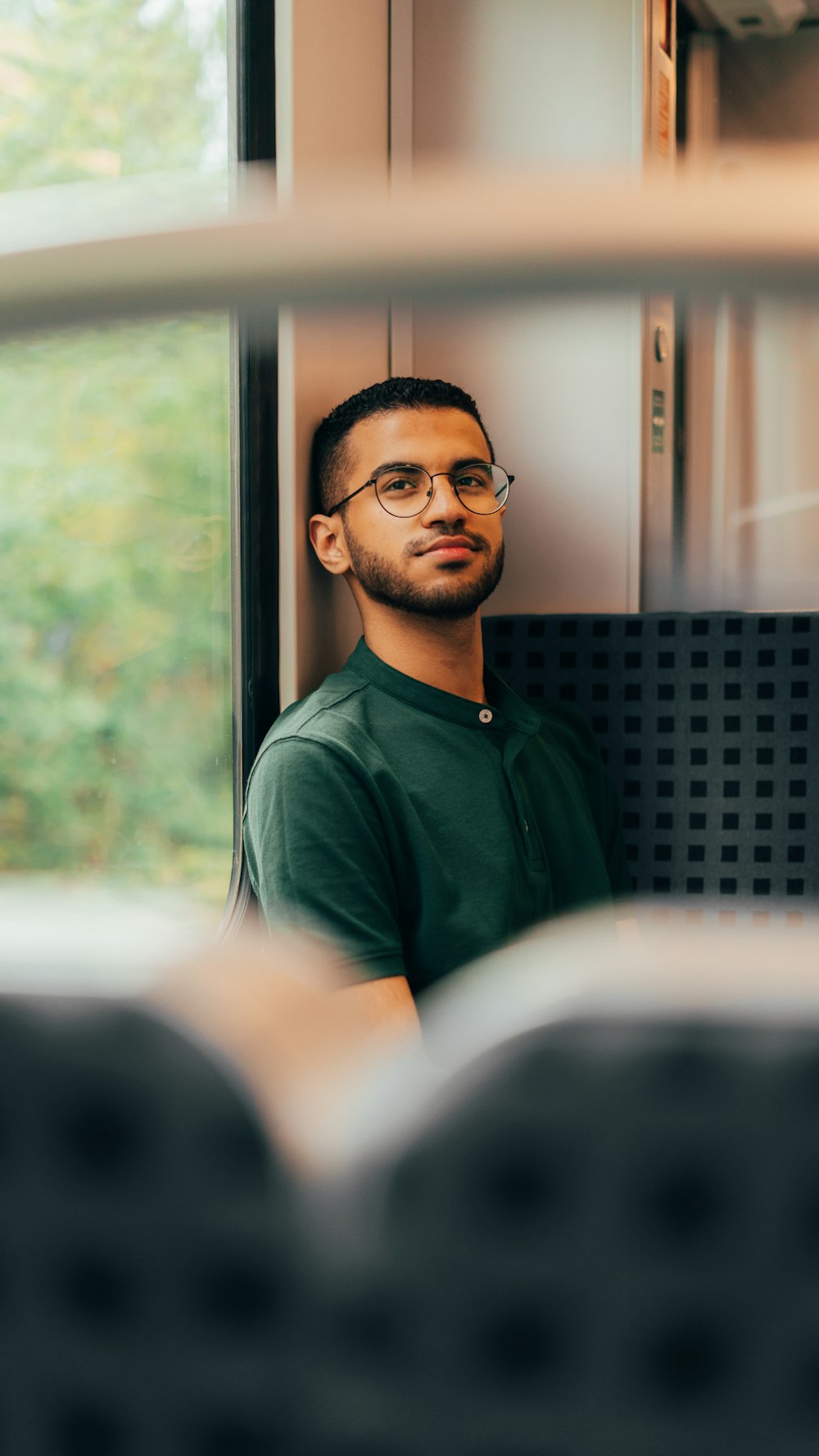 T-shirt girocollo verde che indossa occhiali da vista con montatura nera