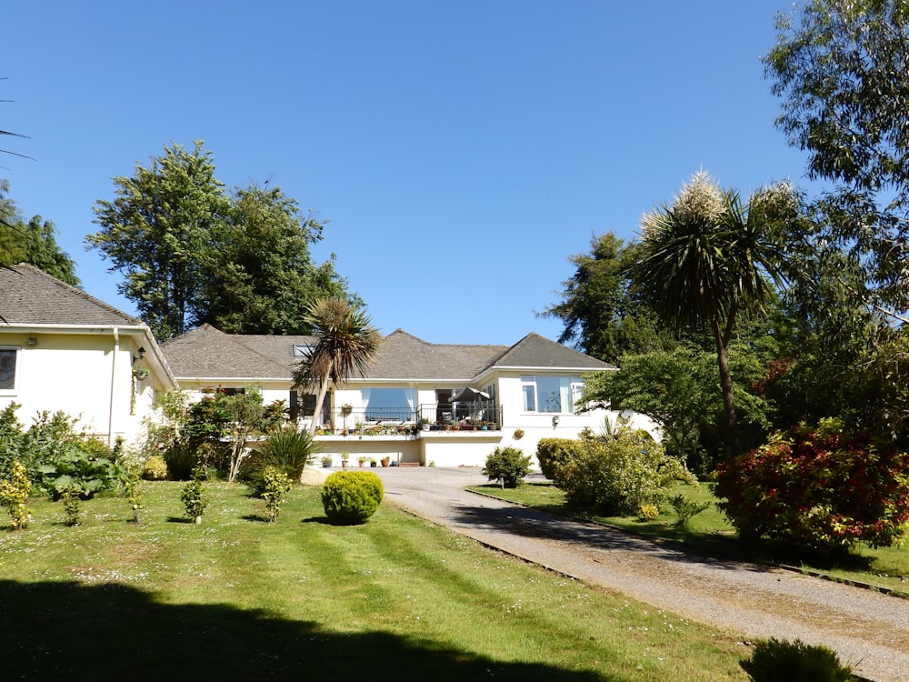 white and gray house near green grass field under blue sky during daytime