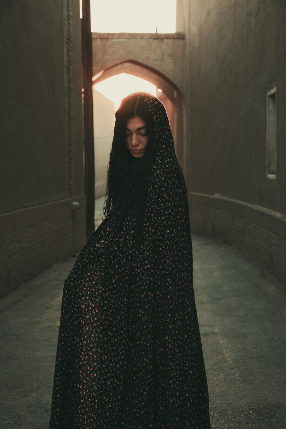 a woman in a black dress standing in a tunnel