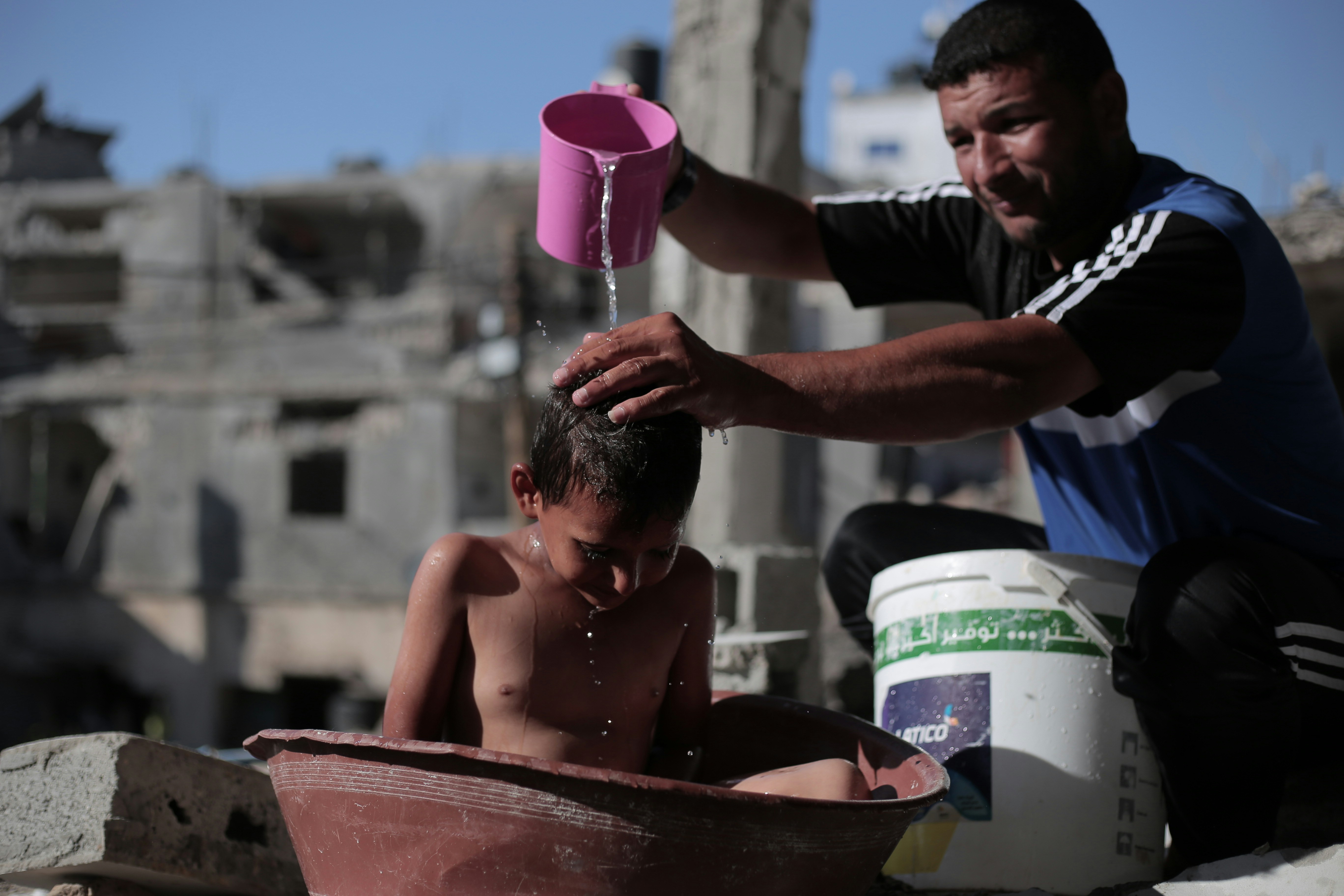 man in black t-shirt sitting on red plastic bucket during daytime