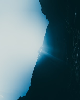 Meg Noel photographing a climber on a sunlit rock face in an Australian wilderness.
