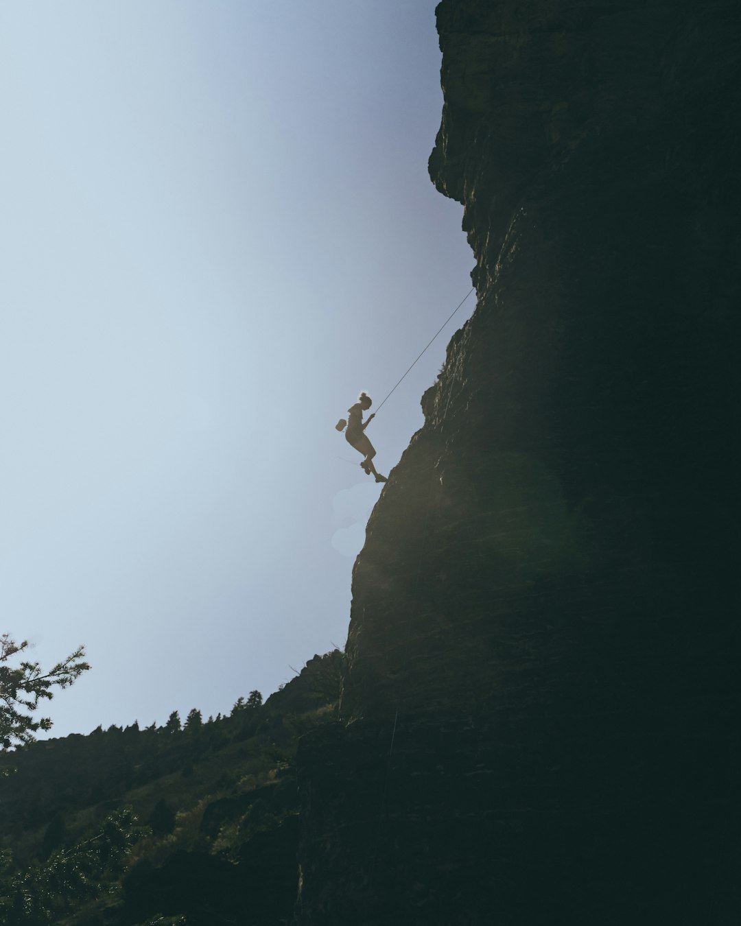 person in white shirt and black shorts climbing on mountain during daytime