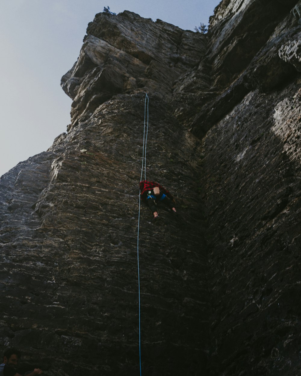 person in red jacket climbing mountain during daytime
