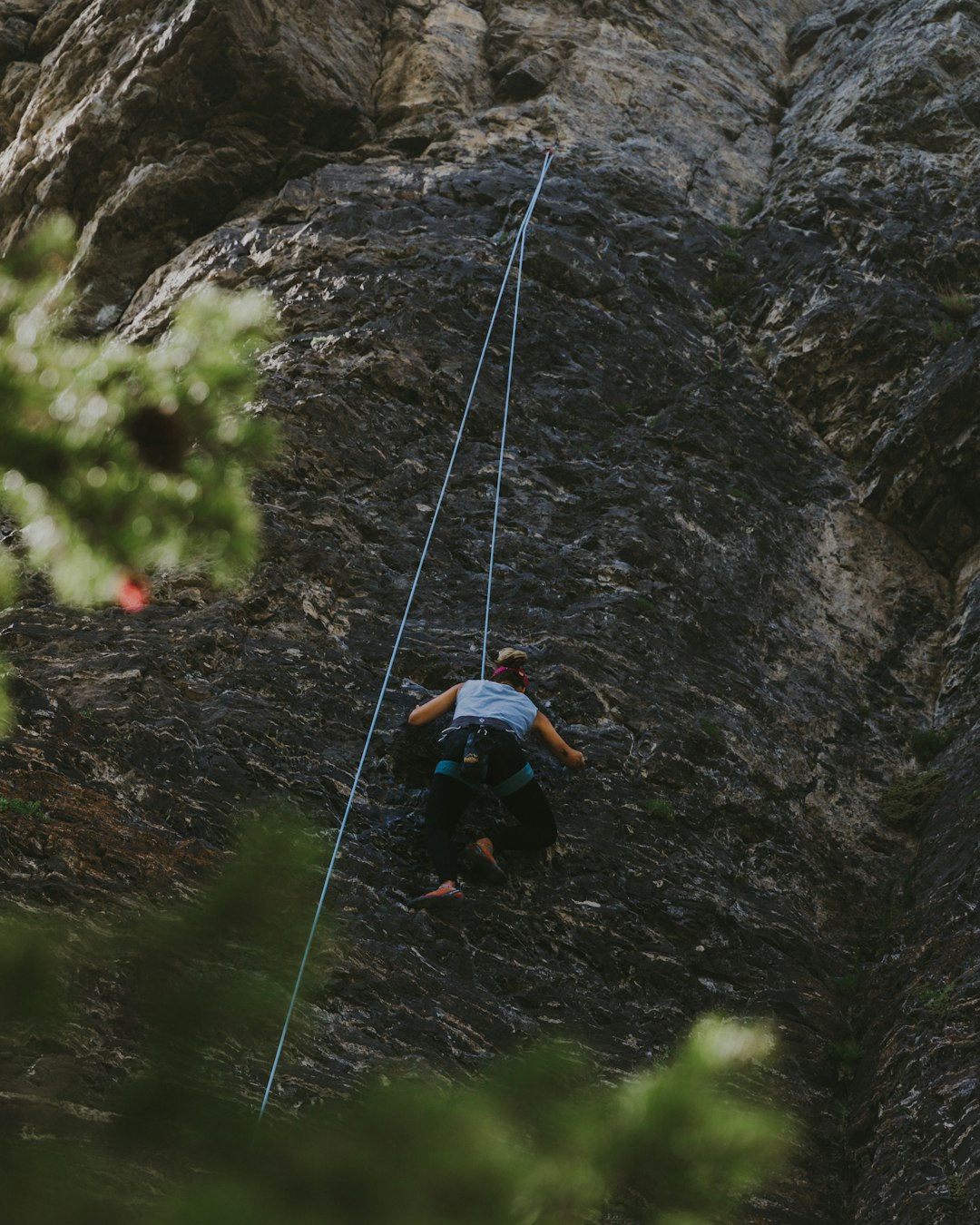 man in black jacket and blue denim jeans climbing on rope