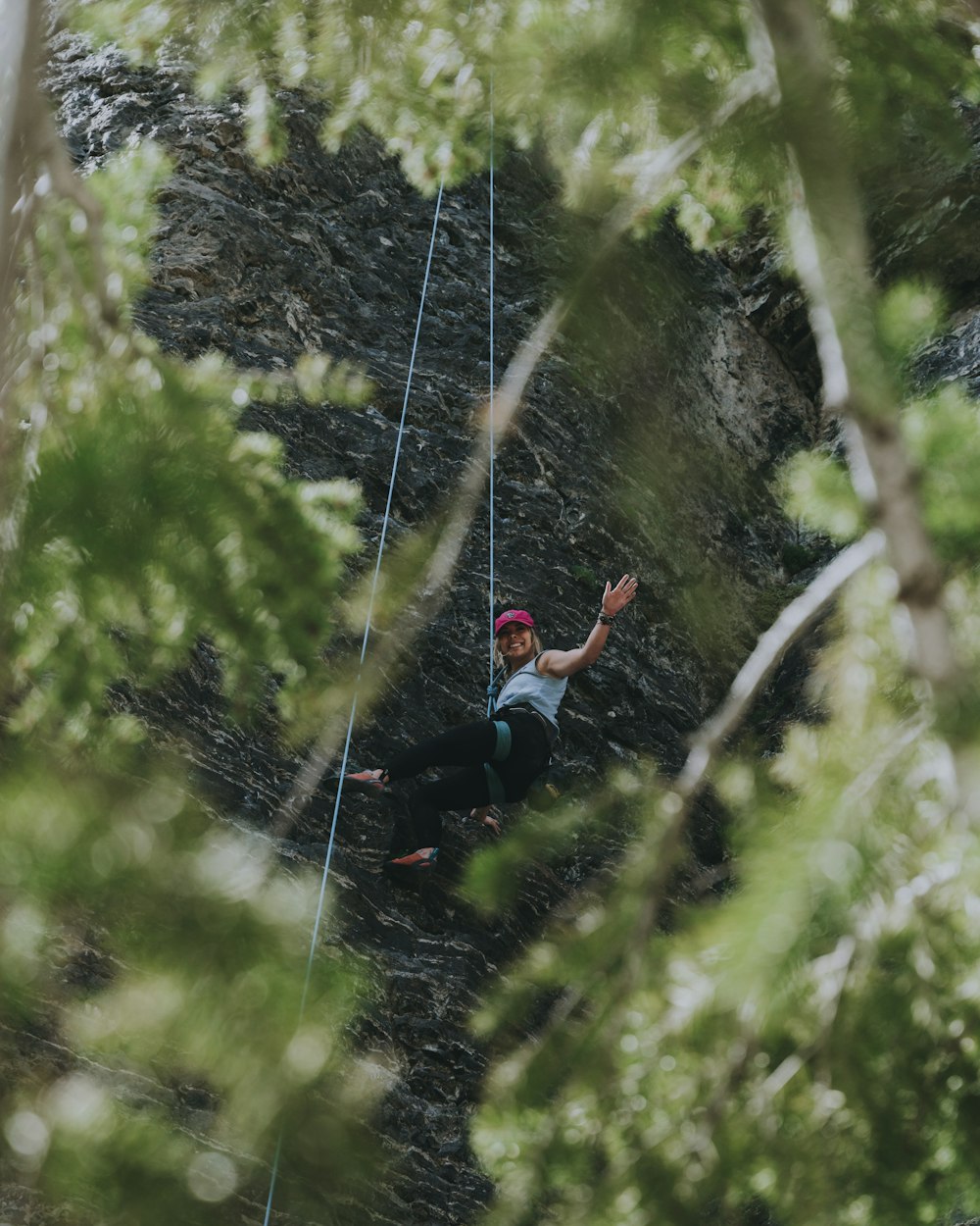 woman in red tank top and black pants climbing on rope during daytime