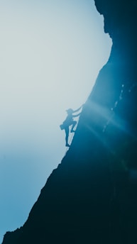 silhouette of man standing on rock formation during daytime