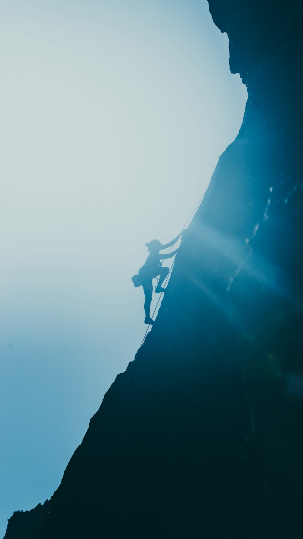 silhouette of man standing on rock formation during daytime