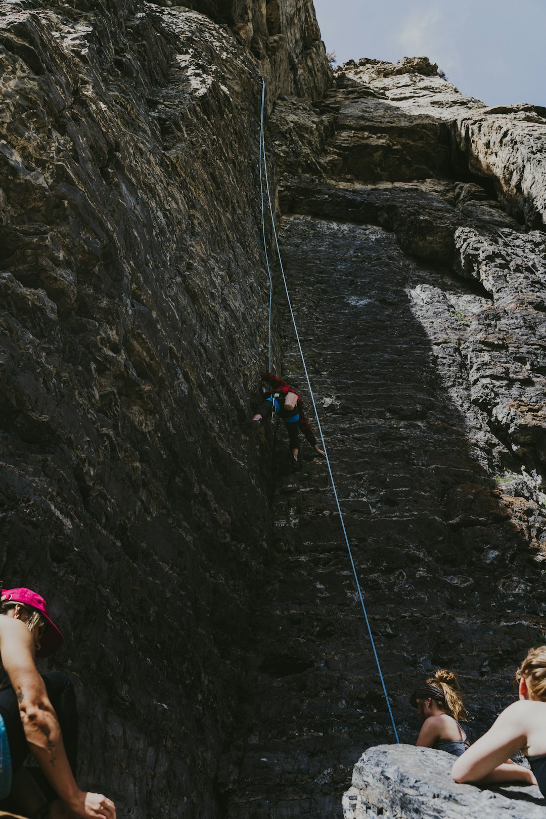 man in black and green jacket climbing on gray rocky mountain during daytime