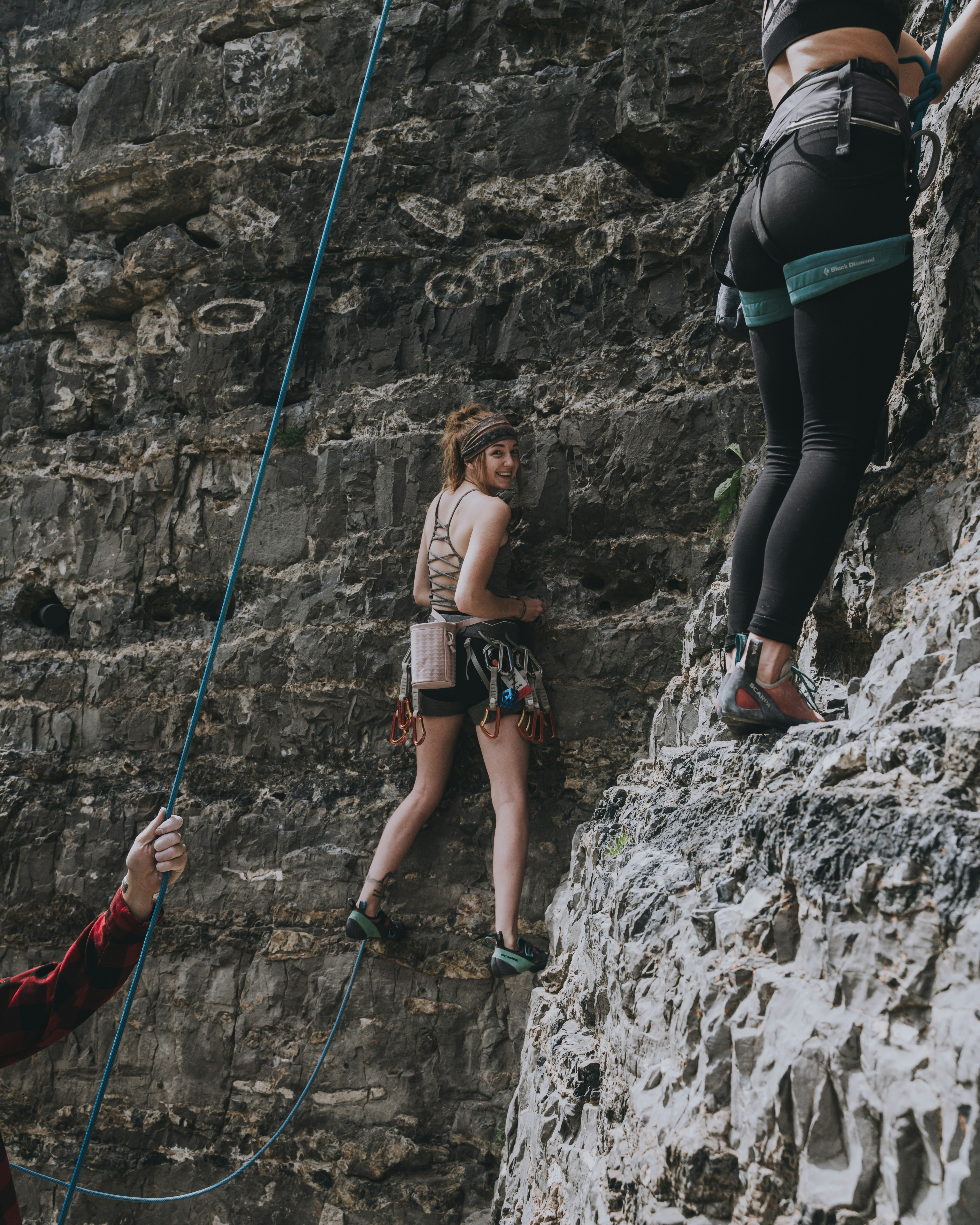 Wanita dengan bra olahraga hitam dan legging hitam memanjat gunung Rocky di siang hari