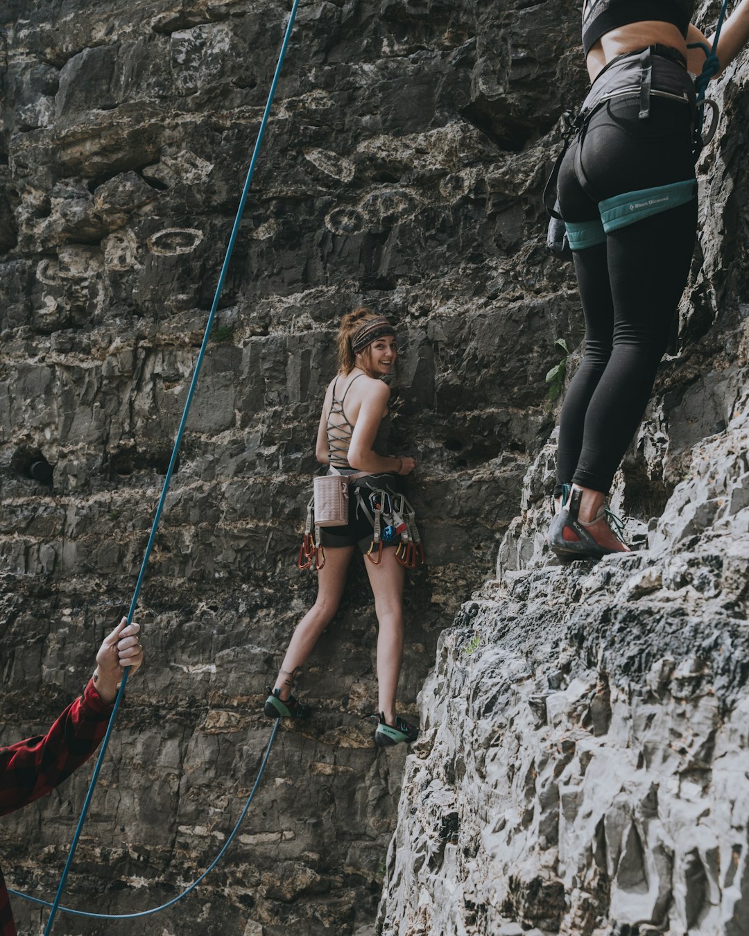 woman in black sports bra and black leggings climbing on rocky mountain during daytime