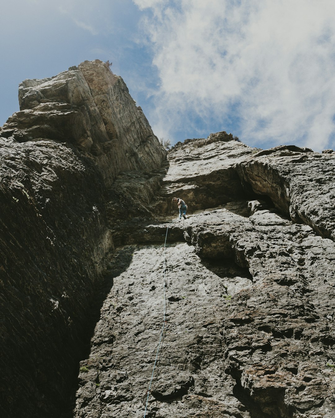 person in blue jacket climbing on rocky mountain during daytime