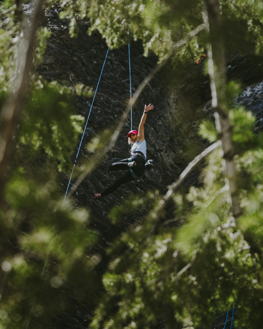 man in red shirt and blue denim jeans hanging on rope during daytime