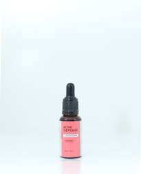 A brown bottle with a black dropper cap, labeled 'ACNE DEFENSE Intensive Serum' on a pink and white label, standing against a plain, light background.