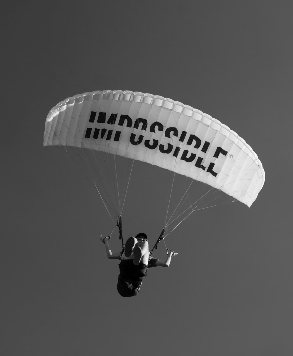hombre con chaqueta negra montado en paracaídas blanco y azul