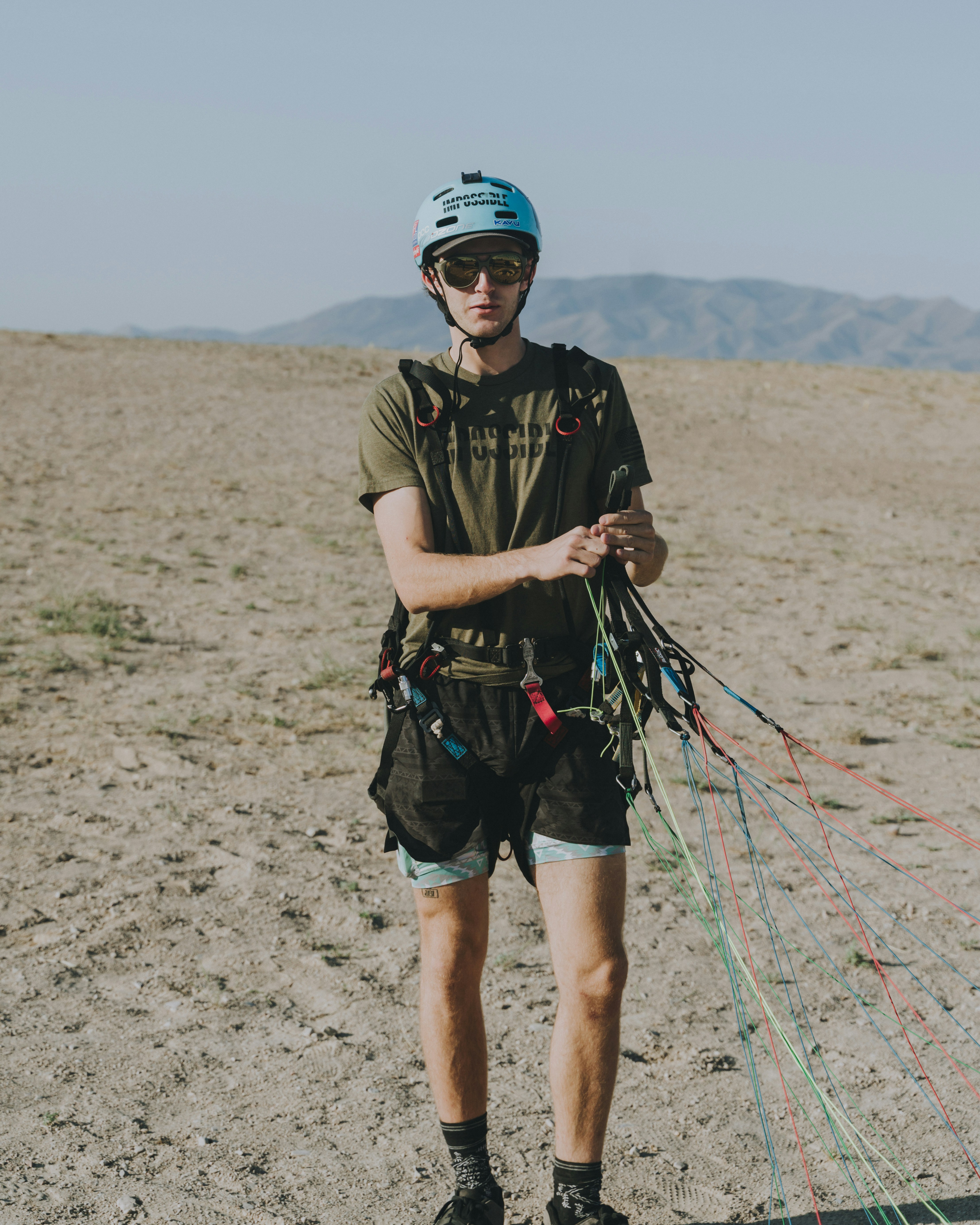 man in black t-shirt and green shorts standing on gray sand during daytime