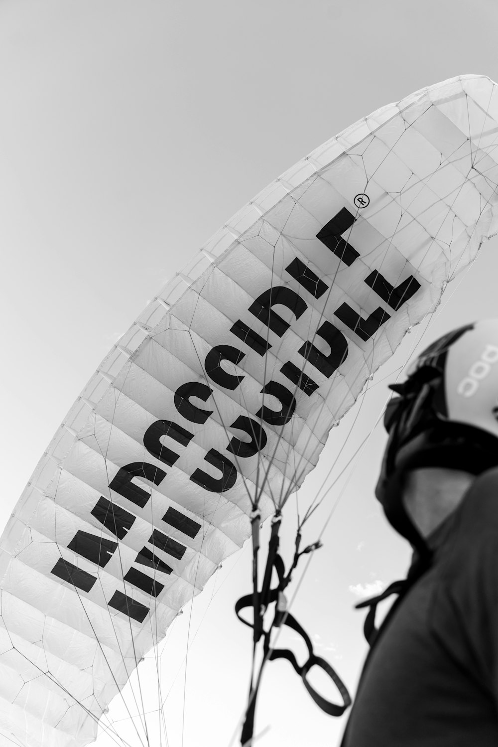 grayscale photo of man in black jacket and helmet riding bicycle