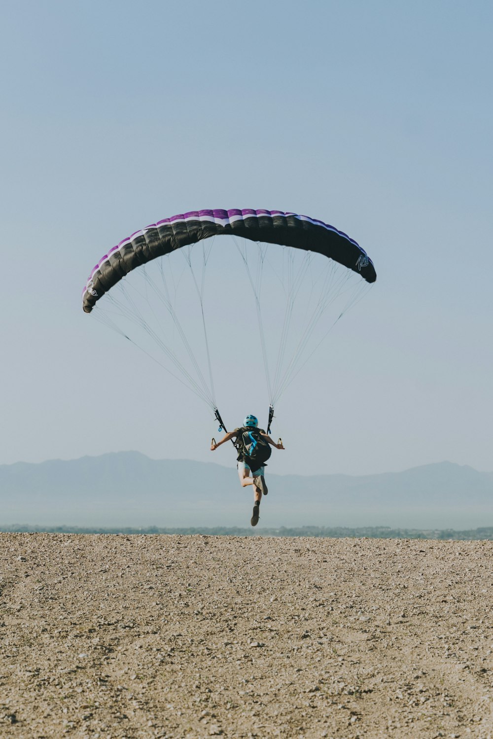 man in blue shirt and black shorts riding on blue and white parachute