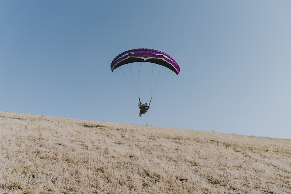 person in red and white parachute in mid air during daytime