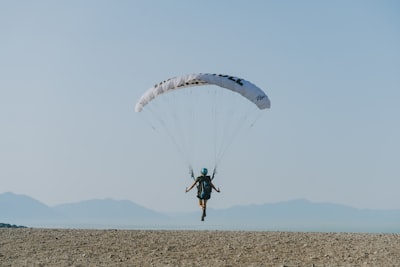 man in black shirt and pants riding on parachute impossible teams background