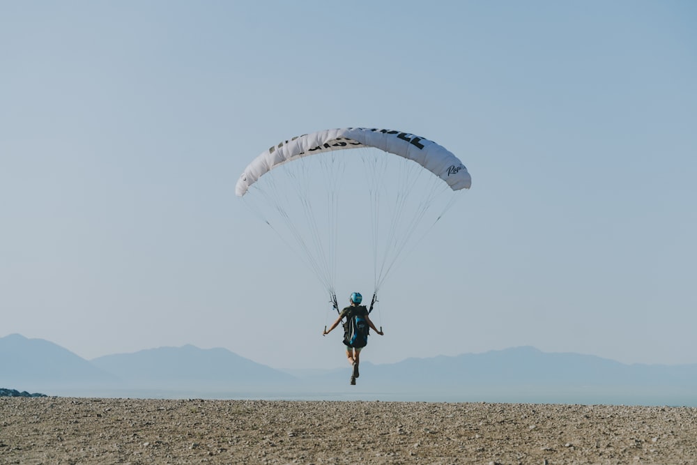 homme en chemise noire et pantalon montant sur le parachute